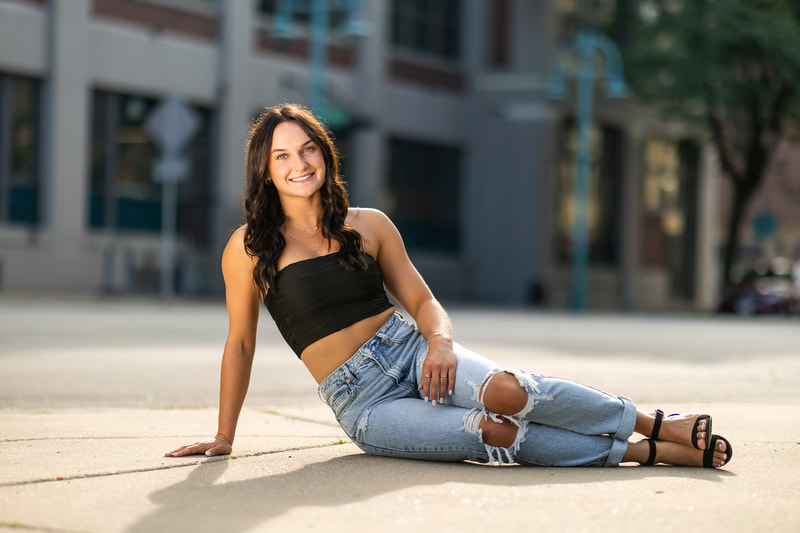 Senior with cropped tube top, ripped skinny jeans and black heels.
